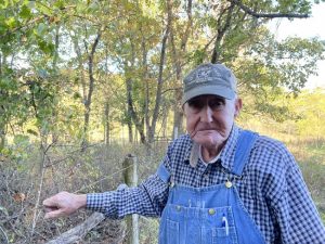 Bob Ziy stands near the fence he built surrounding the graveyard from the Poor Farm on his property.