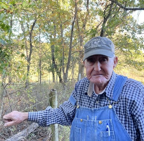 Bob Ziy stands near the fence he built surrounding the graveyard from the Poor Farm on his property.