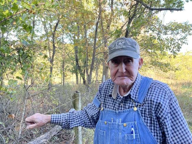 Bob Ziy stands near the fence he built surrounding the graveyard from the Poor Farm on his property.