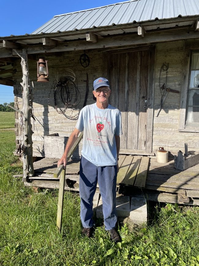 Wayne Simpson in front of cabin